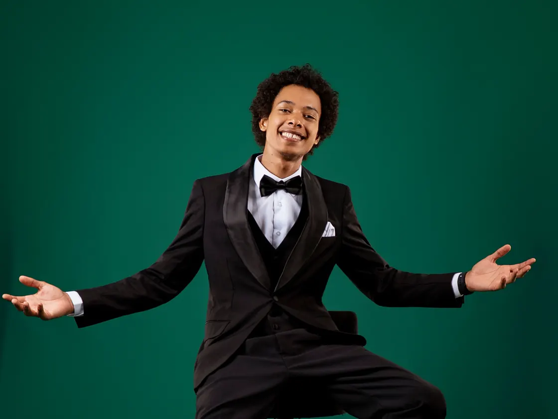 Mister H en smoking, bras ouverts, sur le fond de studio de l'Academy