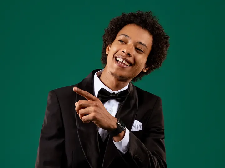 Mister H désignant quelque chose du doigt, sourire complice